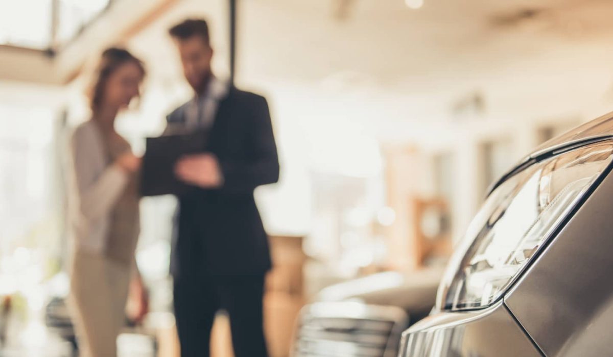 An image of a dealer showing a customer the paperwork for an extended warranty